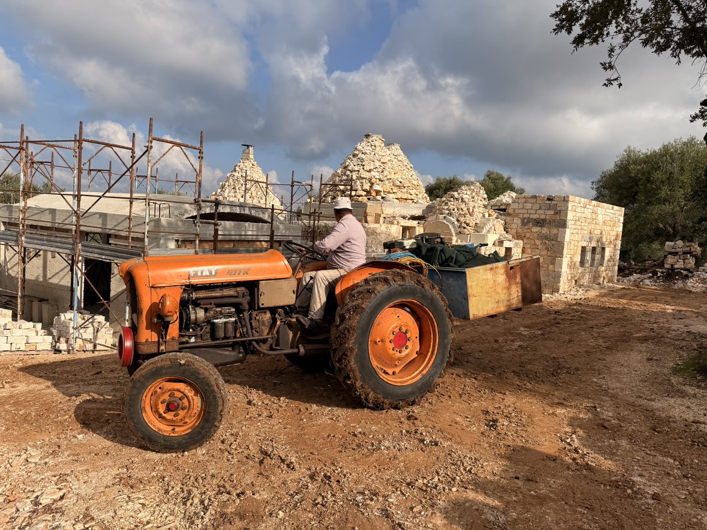 Orange Fiat tractor at trullo construction