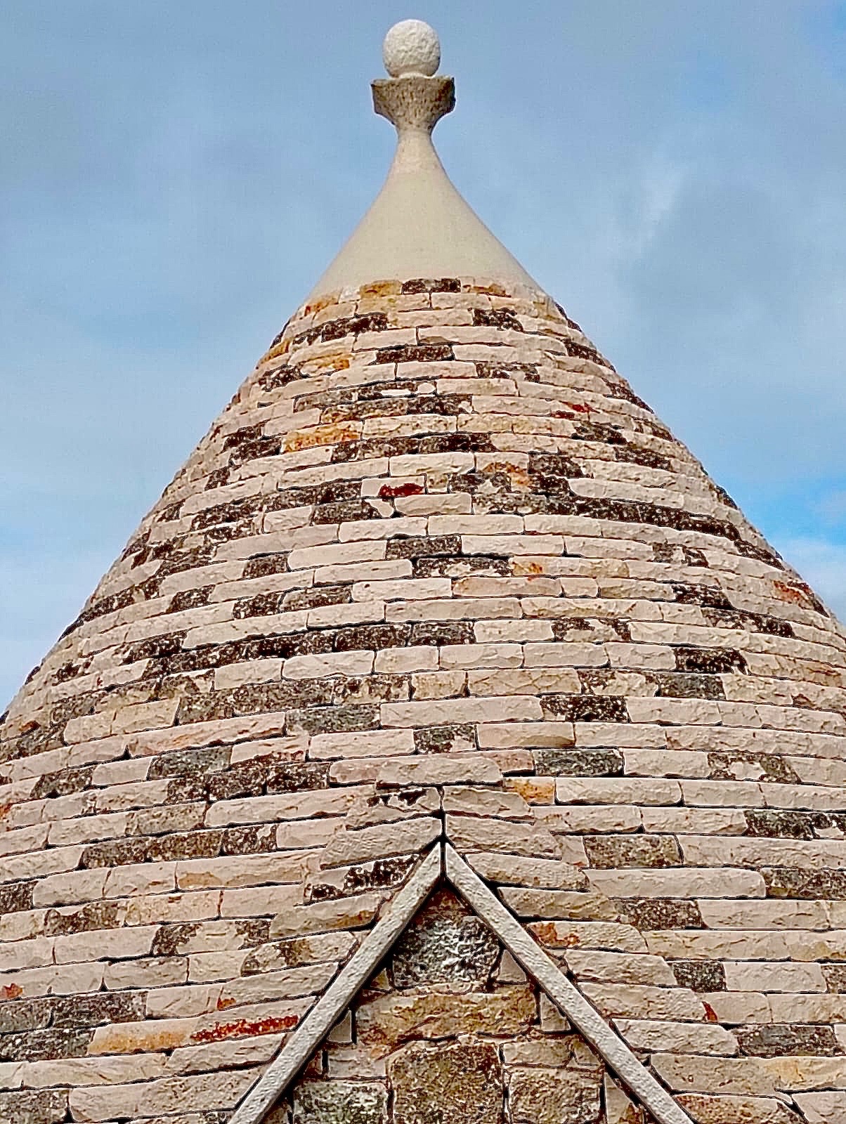 Close-up of the trullo dome pinnacle against a clear blue Puglian sky