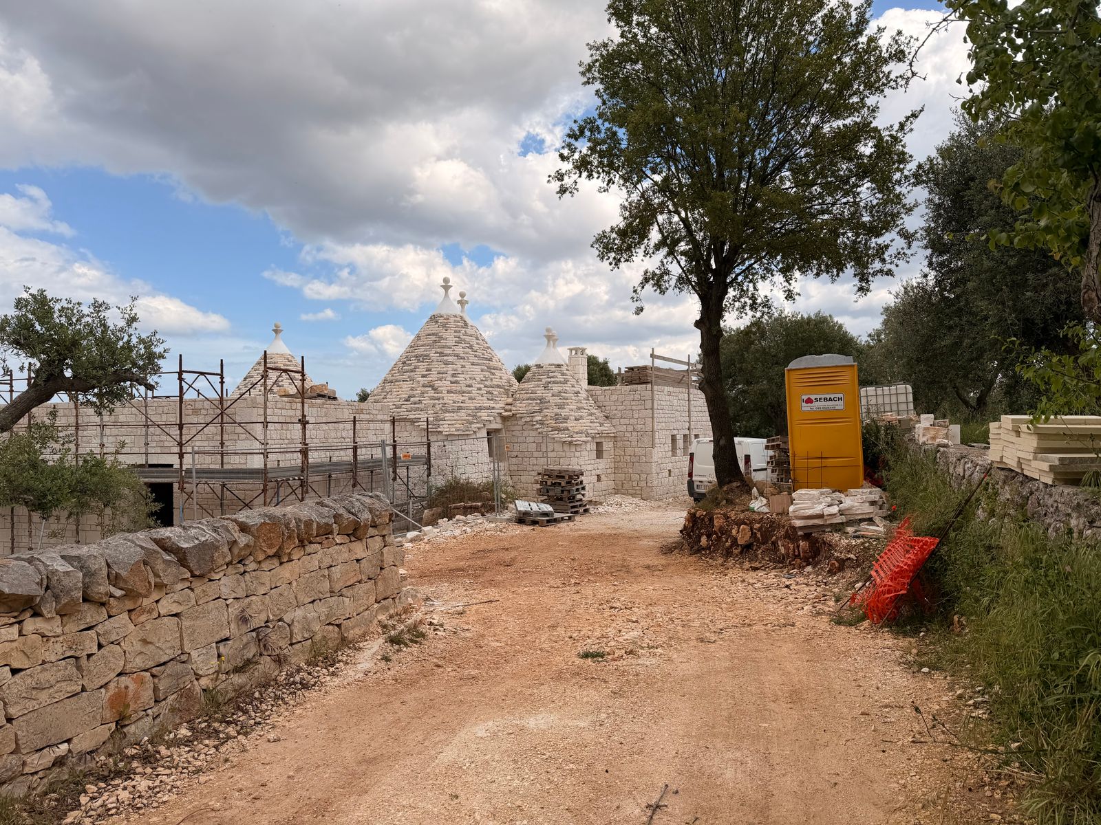 Stone outbuildings under renovation, surrounded by gathered limestone
